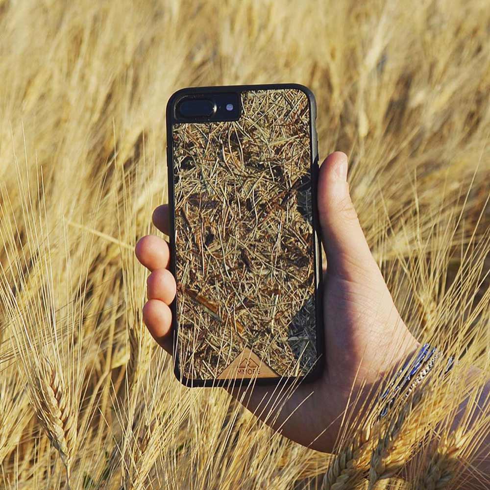 Alpine Hay phone case in hands on the field