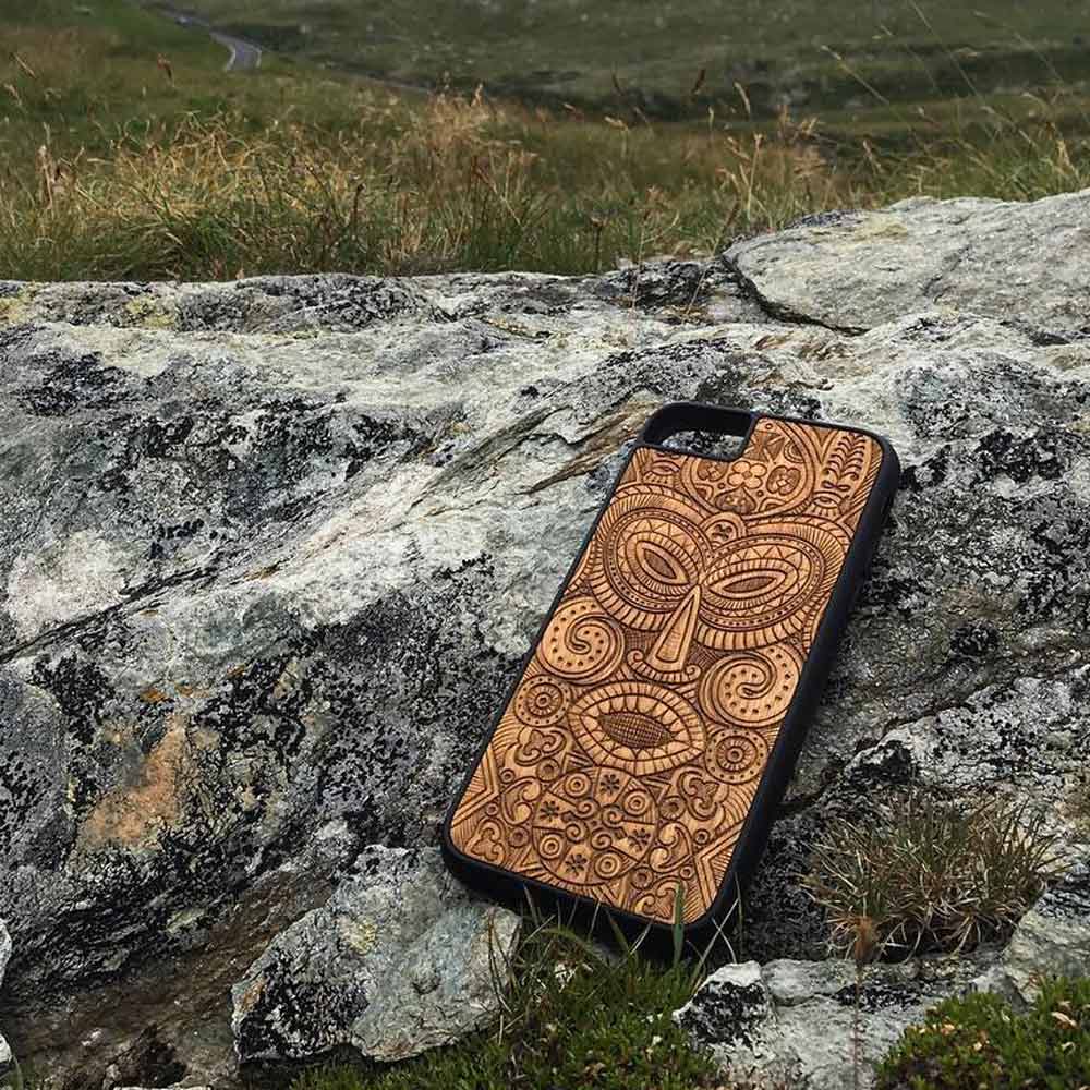 Caja de teléfono con máscara tribal de madera en la naturaleza